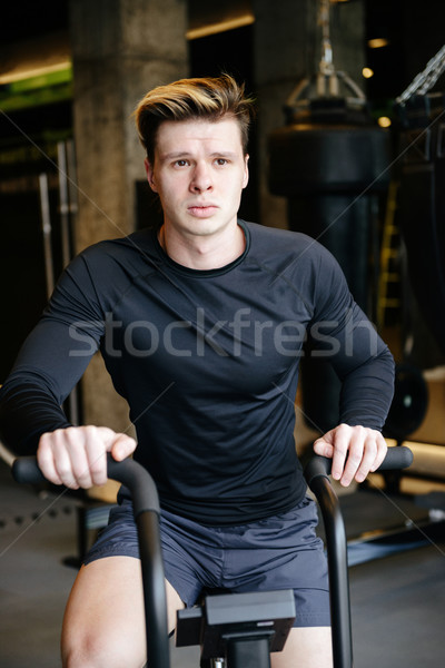 Vertical image of Calm Muscular man using spinning bicycle Stock photo © deandrobot