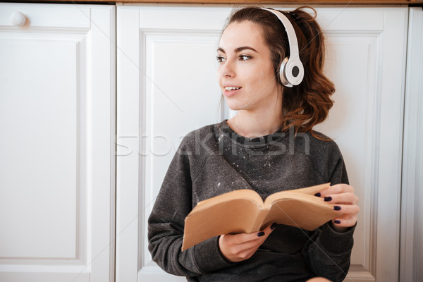 Foto stock: Mulher · ouvir · música · fones · de · ouvido · cozinha · mulher · jovem · leitura