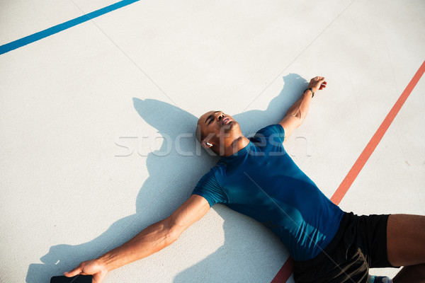 Portrait of a tired young african fitness man in earphones Stock photo © deandrobot