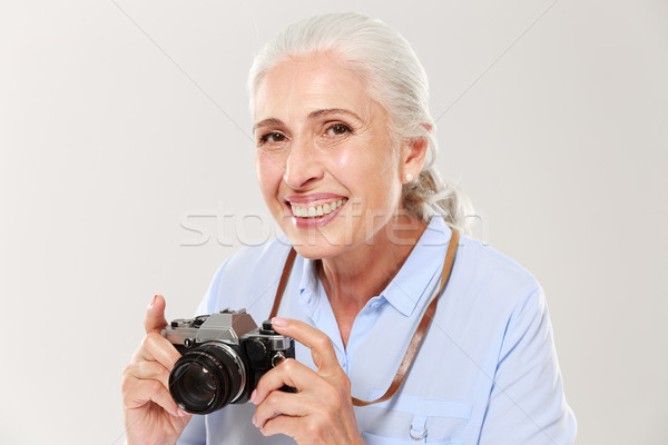 Happy mature woman holding retro camera isolated over white Stock photo © deandrobot