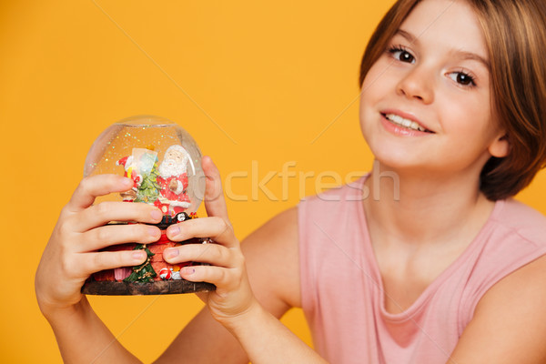 Portrait of beautiful girl looking camera and holding snow globe in hands Stock photo © deandrobot