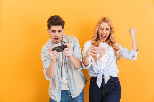 Image of excited young man and woman playing together and compet Stock photo © deandrobot