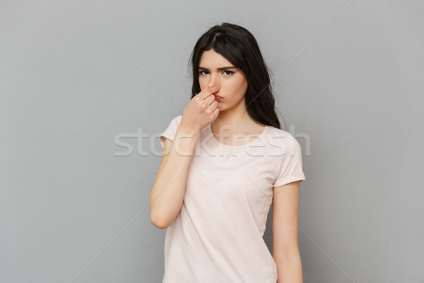 Displeased young lady covering his nose. Stock photo © deandrobot