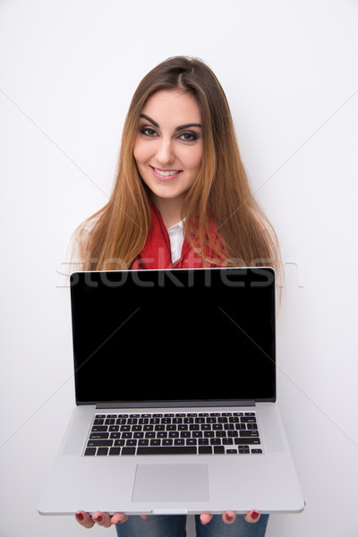 Happy woman showing blank laptop screen over gray background Stock photo © deandrobot