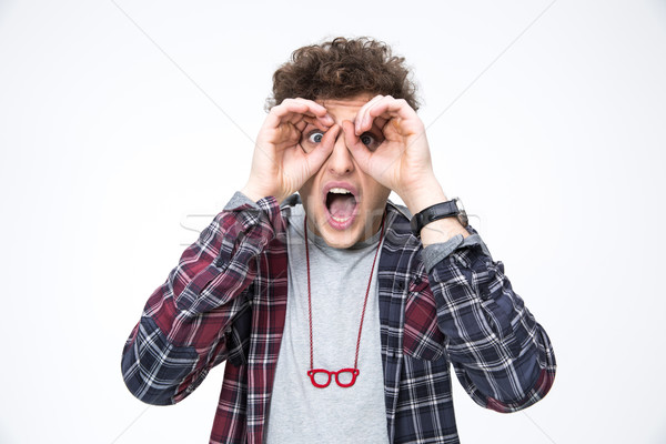 Surprised young man looking through fingers Stock photo © deandrobot