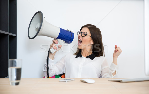 Businesswoman sitting at the table and speaking through megaphone Stock photo © deandrobot