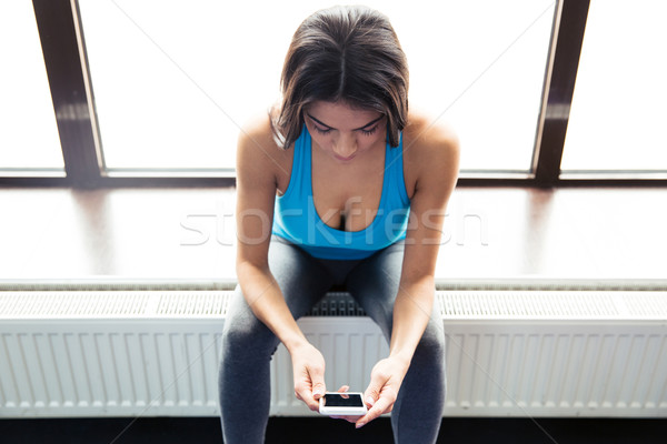 Beautiful fit woman using smartphone Stock photo © deandrobot