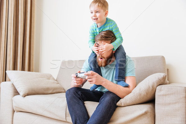 Little boy covering father eyes while he playing computer games Stock photo © deandrobot