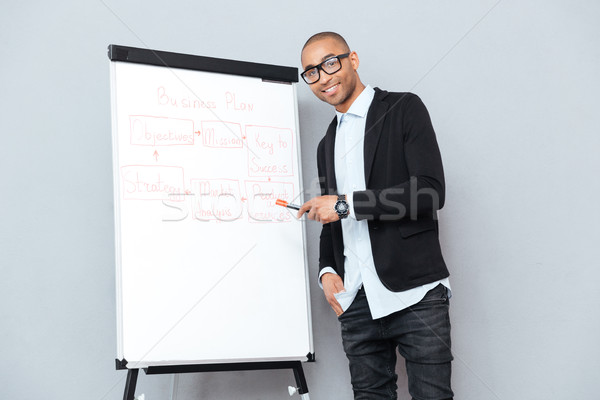 Cheerful african businessman using flipchart and pointing on business plan Stock photo © deandrobot