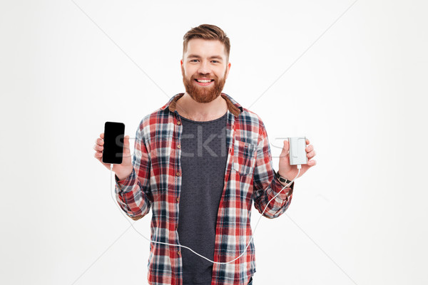 Attractive smiling man charging his mobile phone Stock photo © deandrobot