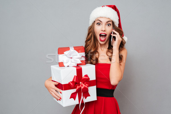 Surprised woman with gifts talks on phone Stock photo © deandrobot