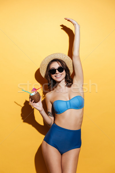 Cheerful young woman in swimwear holding cocktail. Stock photo © deandrobot