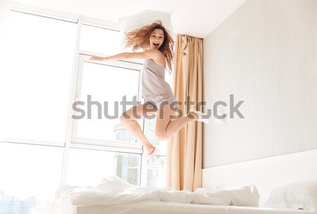 Tineri amuzant femeie jumping pat pernă Imagine de stoc © deandrobot