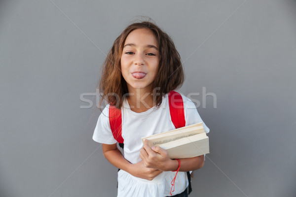 Boldog barna hajú iskolás lány tart könyvek mutat Stock fotó © deandrobot