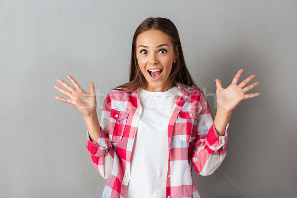 Close up photo of amazed young brunette woman in checkered shirt Stock photo © deandrobot
