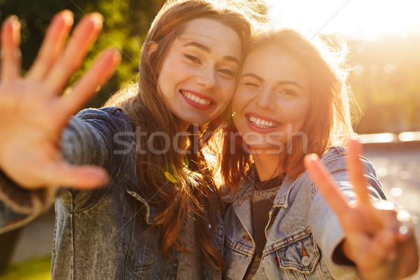 Portrait of two smiling young girls waving to camera Stock photo © deandrobot