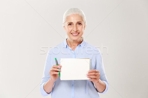 Smiling mature woman showing notebook with copy space for text isolated Stock photo © deandrobot