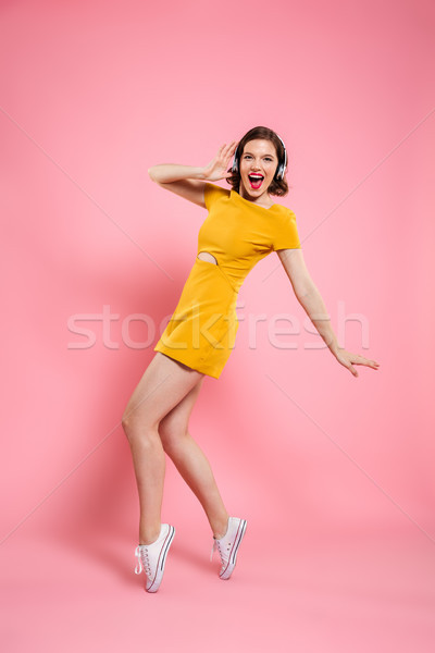Full length portrait of happy charming woman in headphones stand Stock photo © deandrobot
