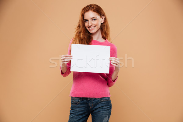 Portrait of a smiling pretty redhead girl holding blank board Stock photo © deandrobot