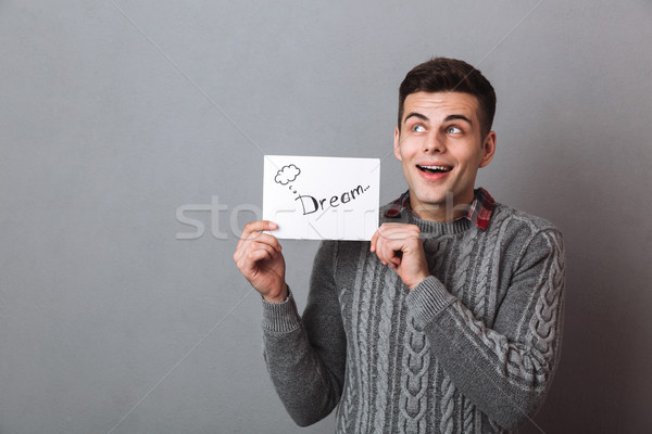 Happy brunette man in sweater holding nameplate dream Stock photo © deandrobot