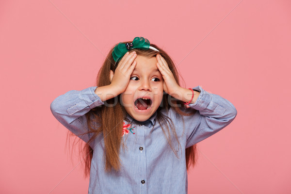 Thrilled little girl reacting emotionally grabbing head with bot Stock photo © deandrobot