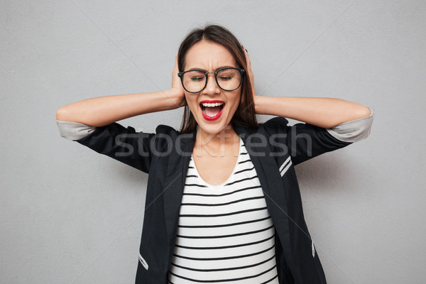 Confused asian business woman in eyeglasses screaming and covering ears Stock photo © deandrobot