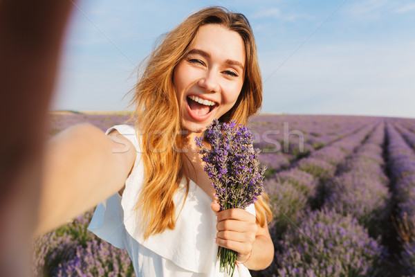 Photo of beautiful young woman in dress taking selfie while hold Stock photo © deandrobot