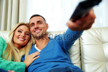 Happy young couple sitting on the sofa and watching TV Stock photo © deandrobot