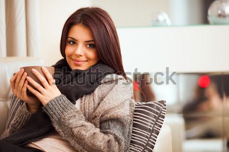 Happy young woman sitting on sofa in cosy cloths with cup of cof Stock photo © deandrobot