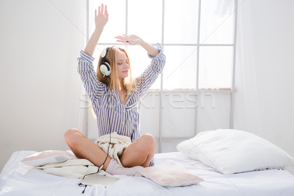 Amusing content girl listening music and dancing on bed Stock photo © deandrobot