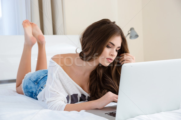 Stock photo: Pensive lovely young woman using laptop and thinking