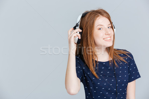 Smiling woman listening music in headphones Stock photo © deandrobot