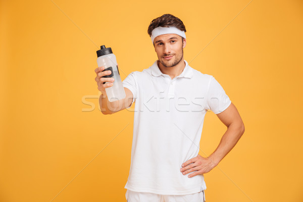 Portrait of a sportsman giving bottle with water at camera Stock photo © deandrobot