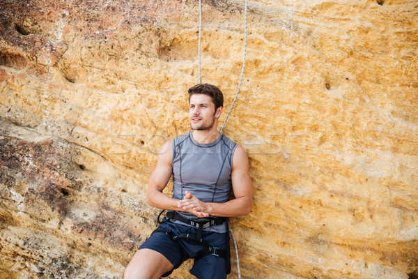 Young handsome sportsman getting ready to climb a cliff Stock photo © deandrobot