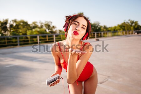 Happy woman in swimwear listening to music and singing outdoors Stock photo © deandrobot