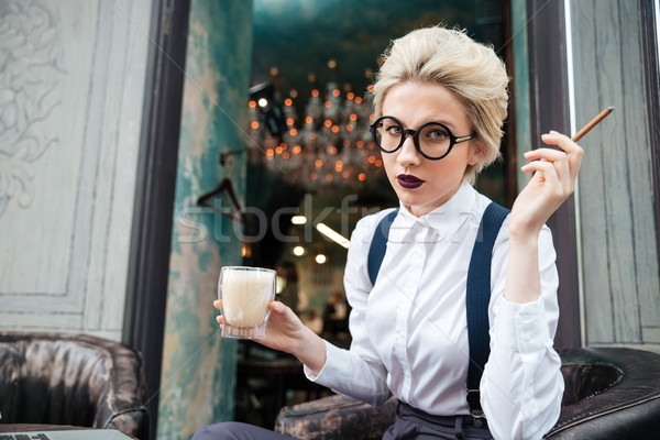 Serious young woman smoking cigarette and drinking coffee in cafe Stock photo © deandrobot