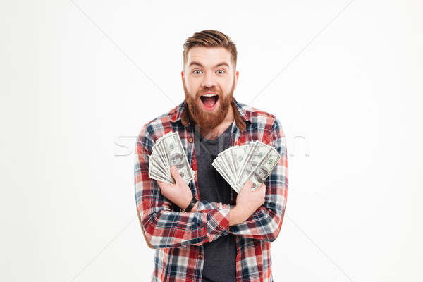 Happy young bearded man in plaid shirt holding dollar bills Stock photo © deandrobot