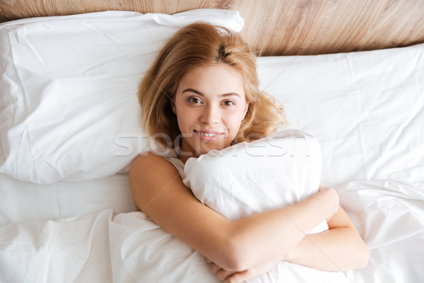 Top vedere femeie zambitoare pernă pat uita Imagine de stoc © deandrobot