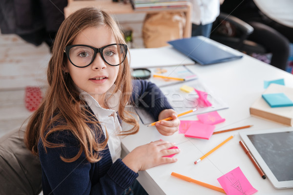 Happy little girl in glasses writing at the table Stock photo © deandrobot