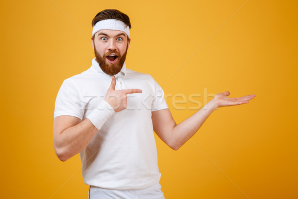 Surprised sportsman pointing at the invisible copyspace on pound Stock photo © deandrobot