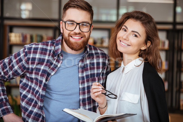 Two happy young students studying together in public library Stock photo © deandrobot