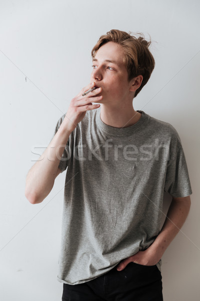 Vertical image of young man smoking cigarette Stock photo © deandrobot