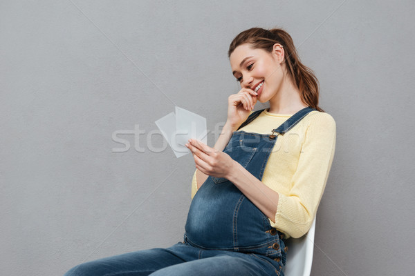 Pregnant cheerful woman holding ultrasound scans Stock photo © deandrobot