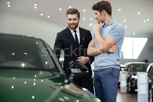 Young male car salesman showing a new car Stock photo © deandrobot