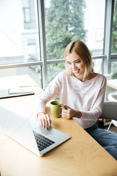 Happy lady sitting in office coworking while using laptop Stock photo © deandrobot