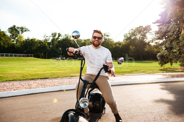 Happy bearded man in sunglasses sitting on modern motorbike Stock photo © deandrobot