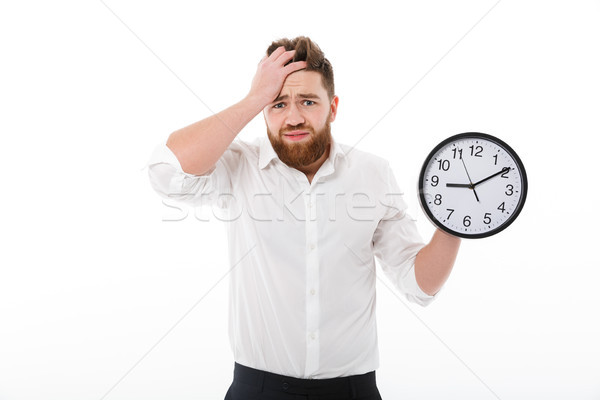 Confused bearded man in business clothes holding clock Stock photo © deandrobot