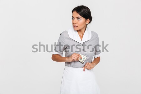 Close-up portrait of young concerned maid in uniform hiding doll Stock photo © deandrobot