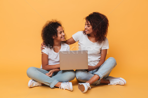 Two cheerful afro american sisters holding laptop computer Stock photo © deandrobot