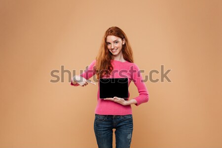 Portrait of a happy pretty redhead girl texting Stock photo © deandrobot